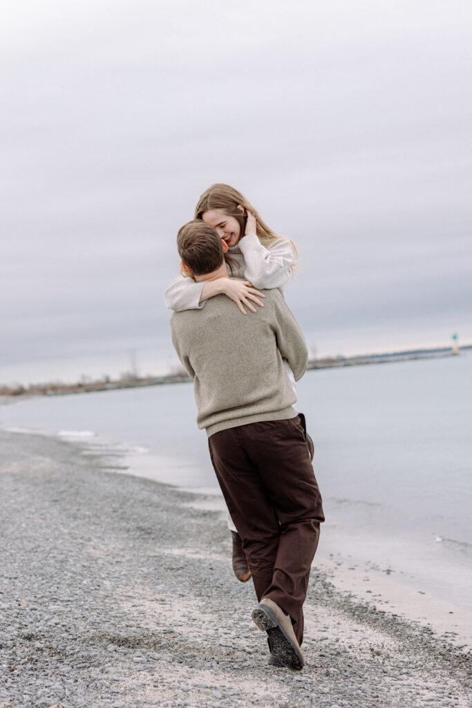 romantic engagement photos of a couple by Lake Ontario with soft light and natural movement