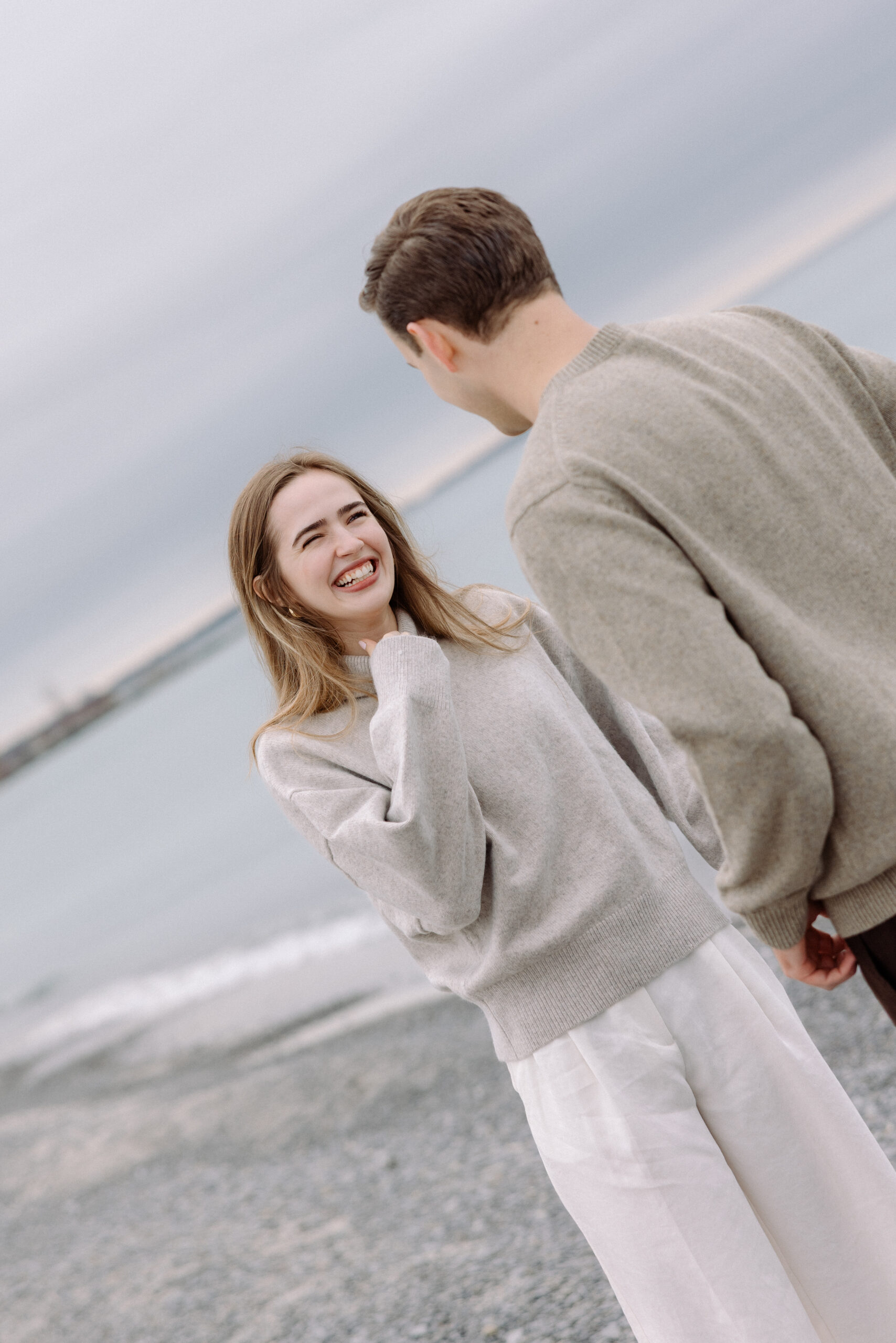 romantic engagement photos of a couple by Lake Ontario with soft light and natural movement