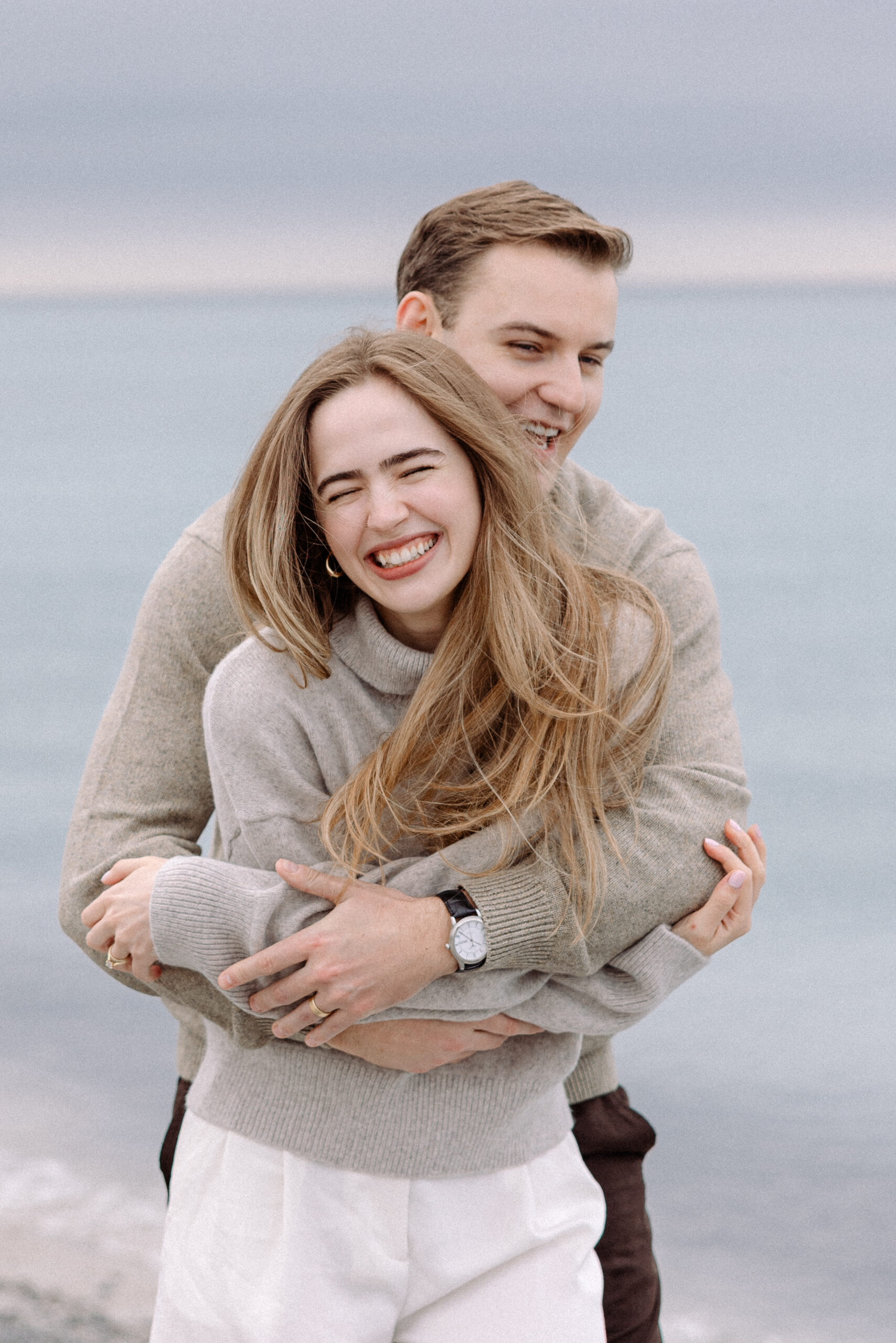 romantic engagement photos of a couple by Lake Ontario with soft light and natural movement