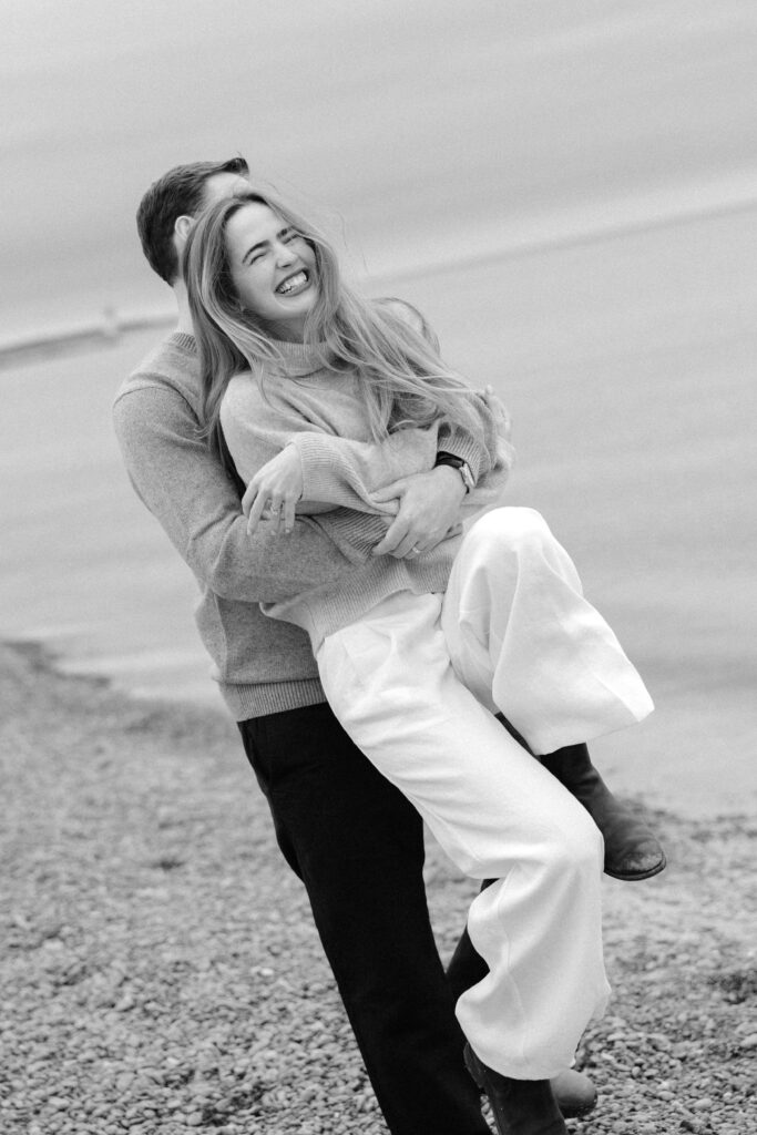 romantic engagement photos of a couple by Lake Ontario with soft light and natural movement