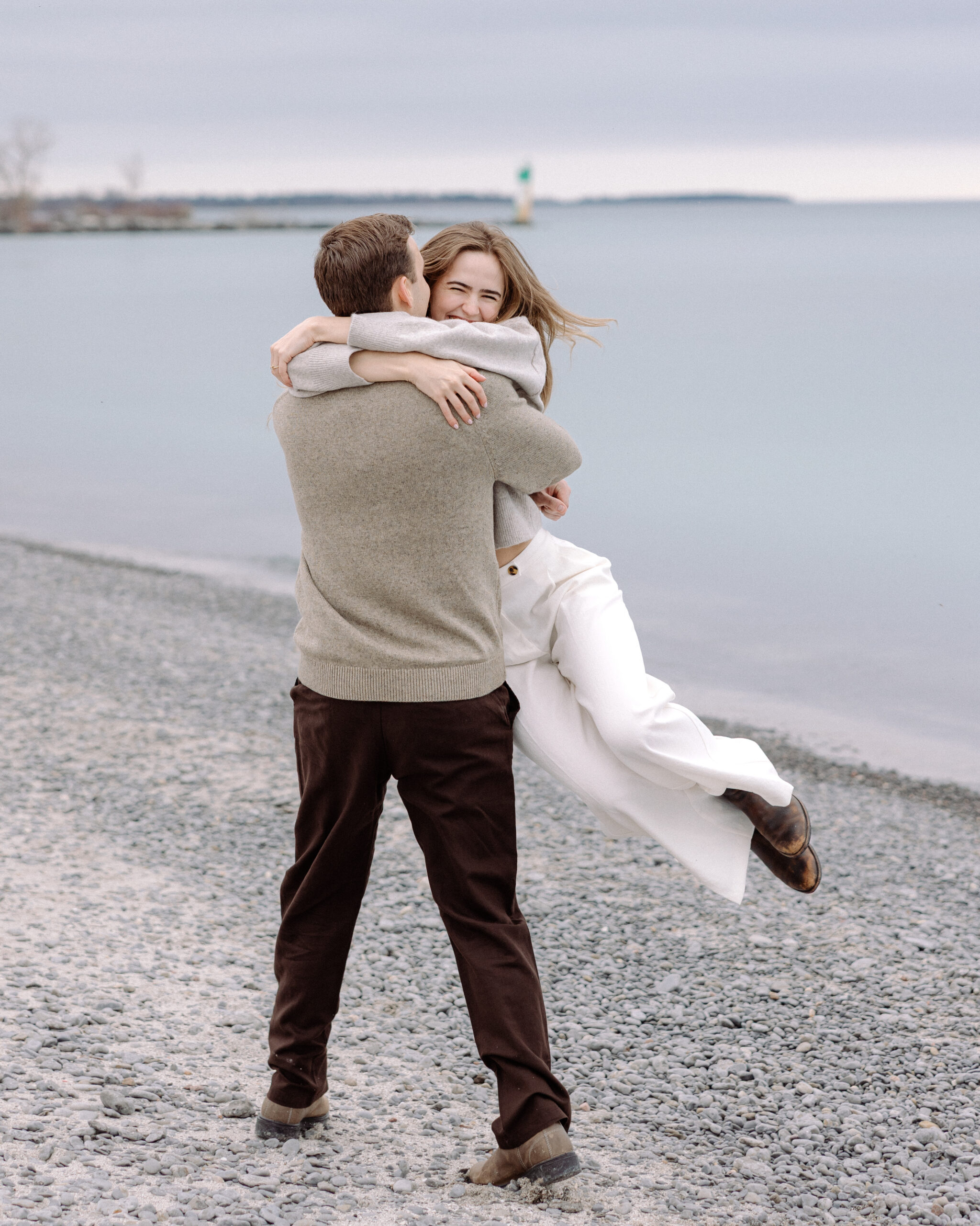romantic engagement photos of a couple by Lake Ontario with soft light and natural movement