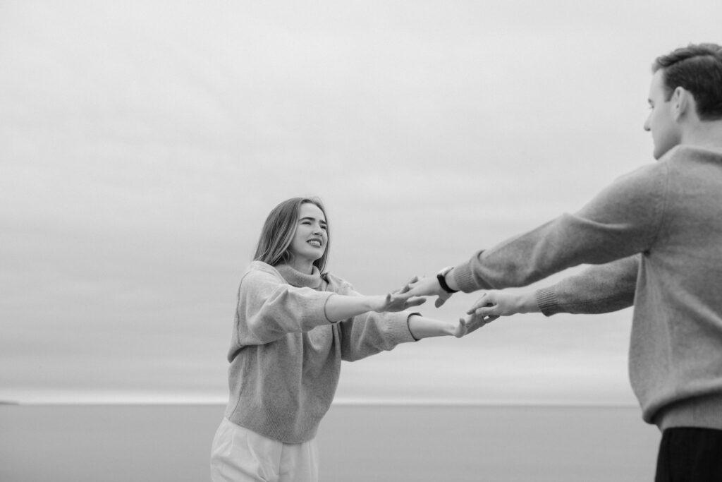 romantic engagement photos of a couple by Lake Ontario with soft light and natural movement
