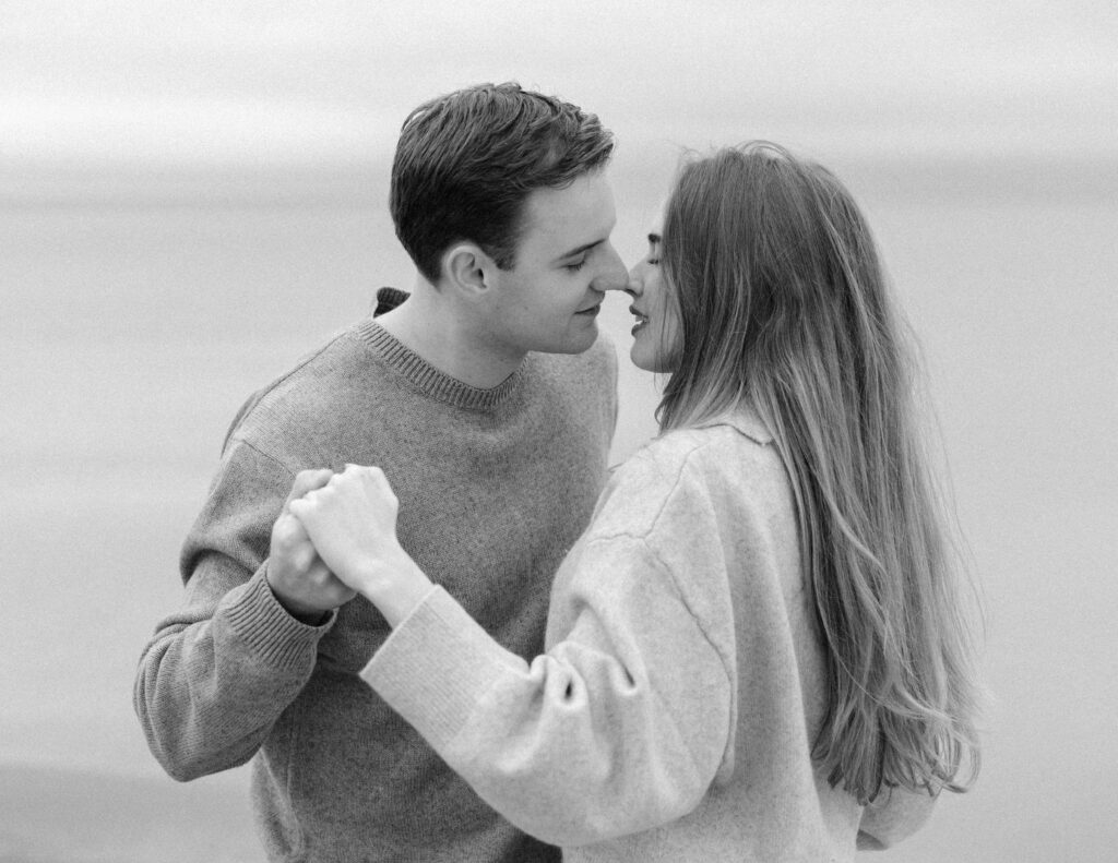 romantic engagement photos of a couple by Lake Ontario with soft light and natural movement