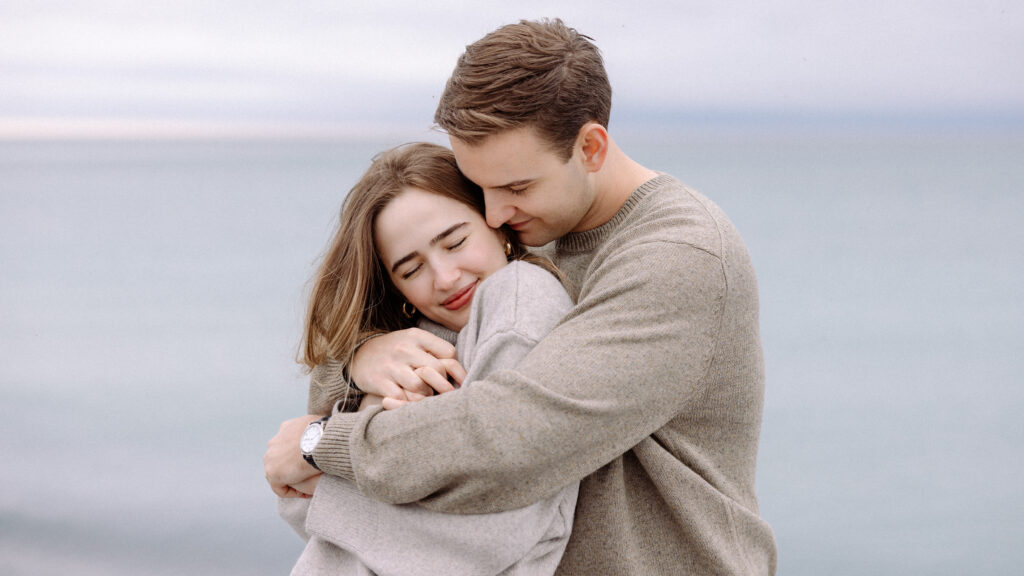 romantic engagement photos of a couple by Lake Ontario with soft light and natural movement